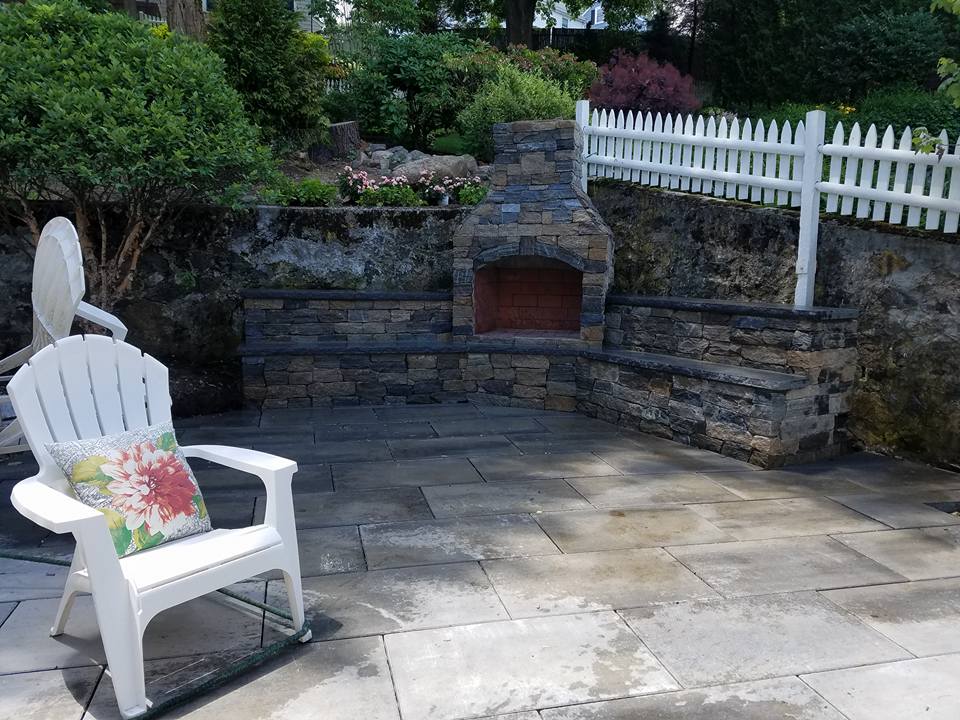 Stone outdoor fireplace and seat wall on a stone patio